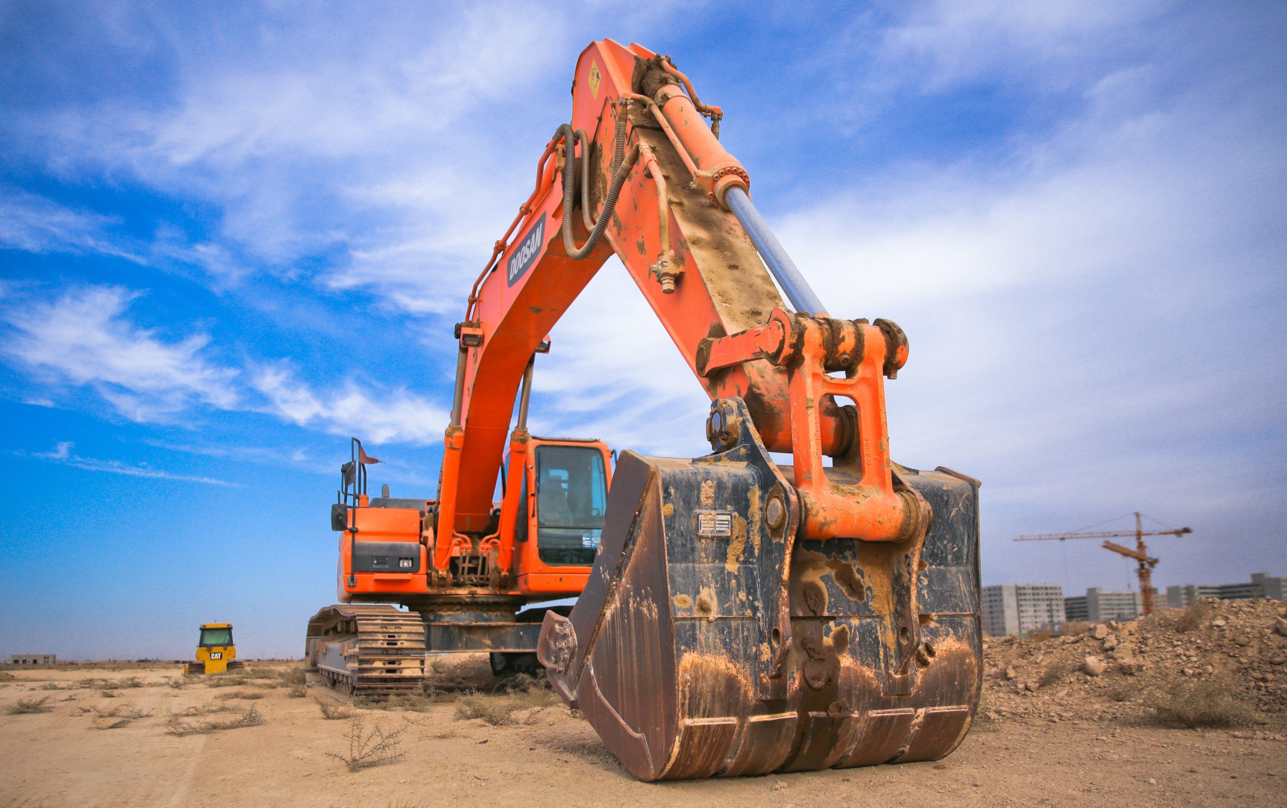 low-angle-photography-of-orange-excavator-under-white-clouds-1078884